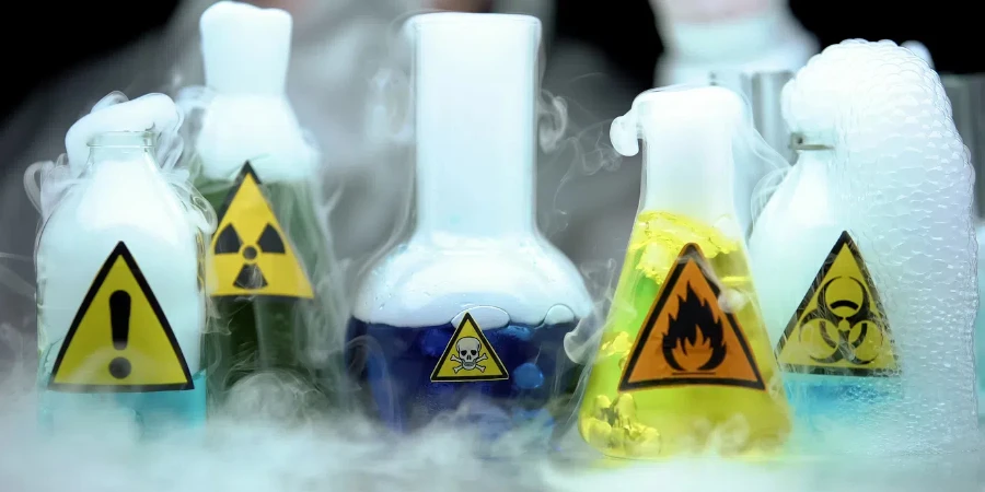 Marked dangerous liquids evaporating in flasks in front laboratory worker