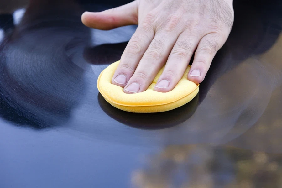 Person polishing car using yellow applicator