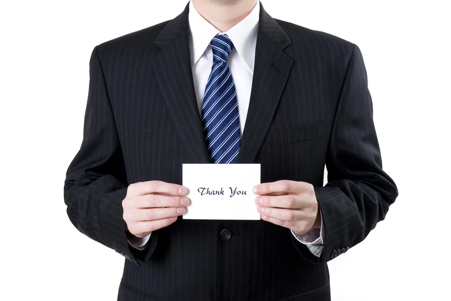 Professionally dressed man holding a thank-you card to show gratitude