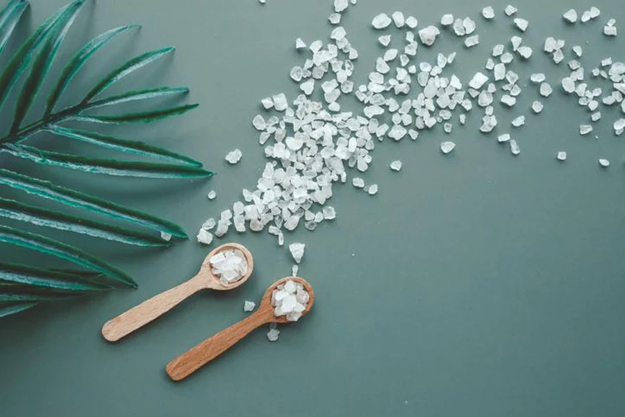 Sea salt on green background in wooden spoon top view