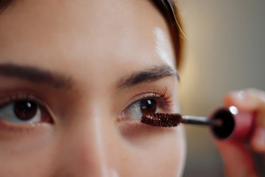 Selective focus, Eye of Attractive young woman looking in the mirror while enjoying applying mascara ready for a beauty routine in the morning at home, Beauty and skincare concept.