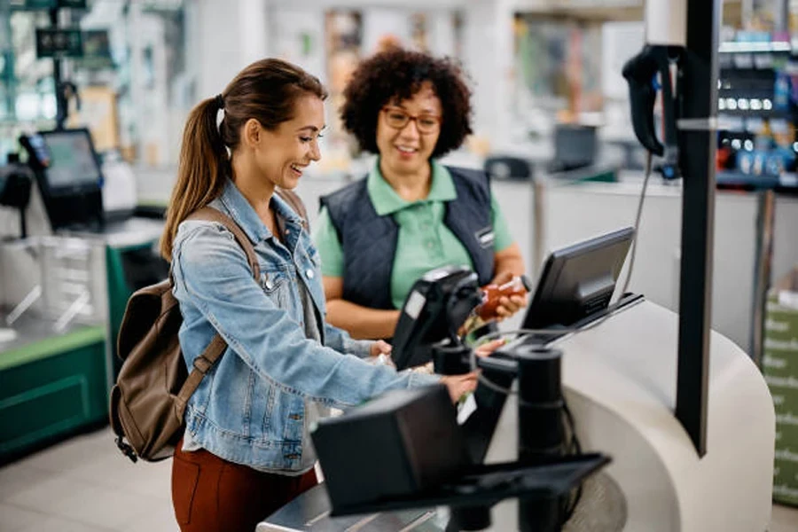 Staff helping a lady with the self-checkout system