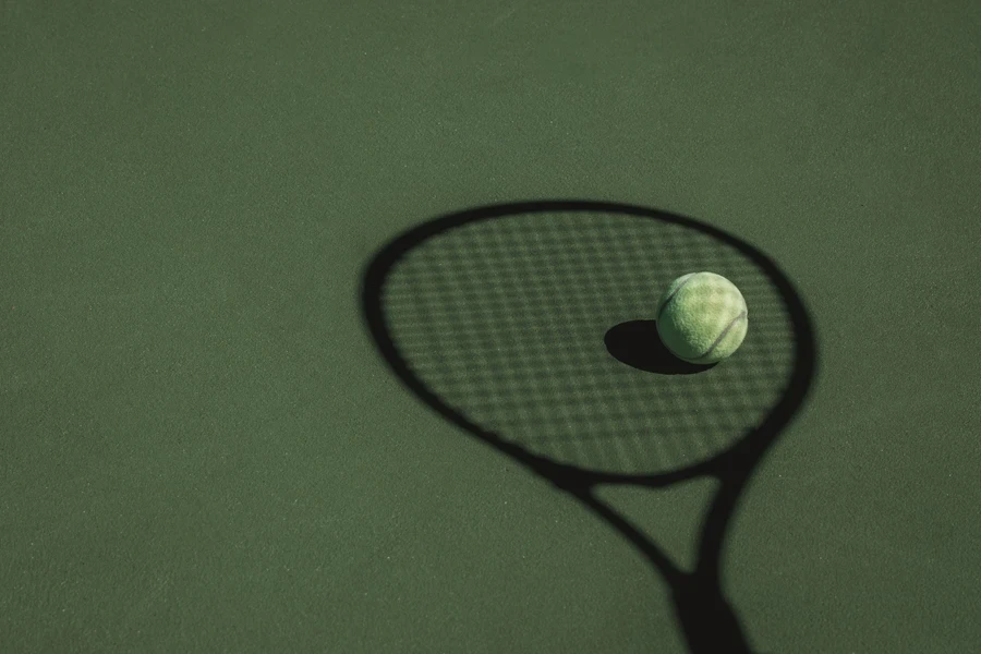 Tennis Ball Sits In The Shadow Cast By A Tennis Racket