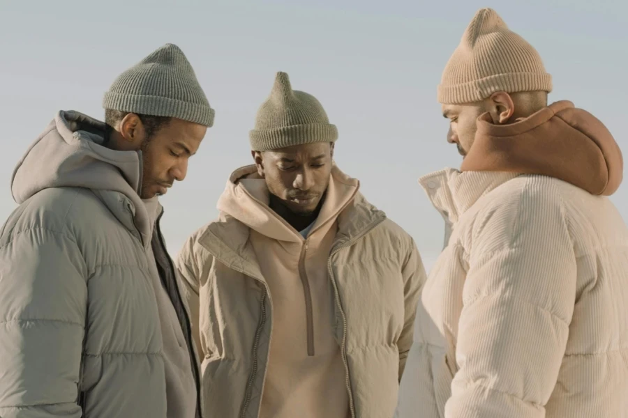 Three men wearing different colored, knitted beanies