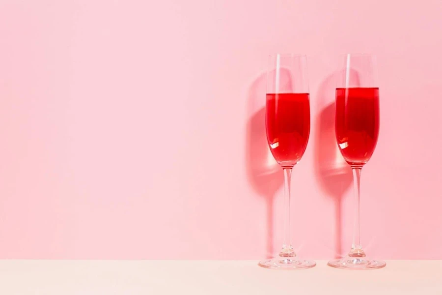 Two Champagne Glasses with Red Cocktails on a Pink Background