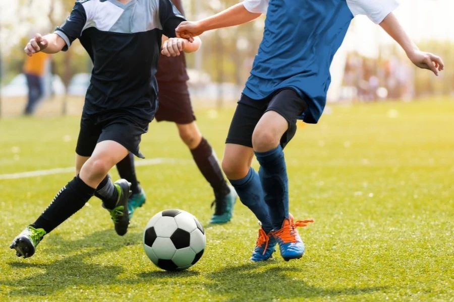 Two soccer players running and kicking a soccer ball