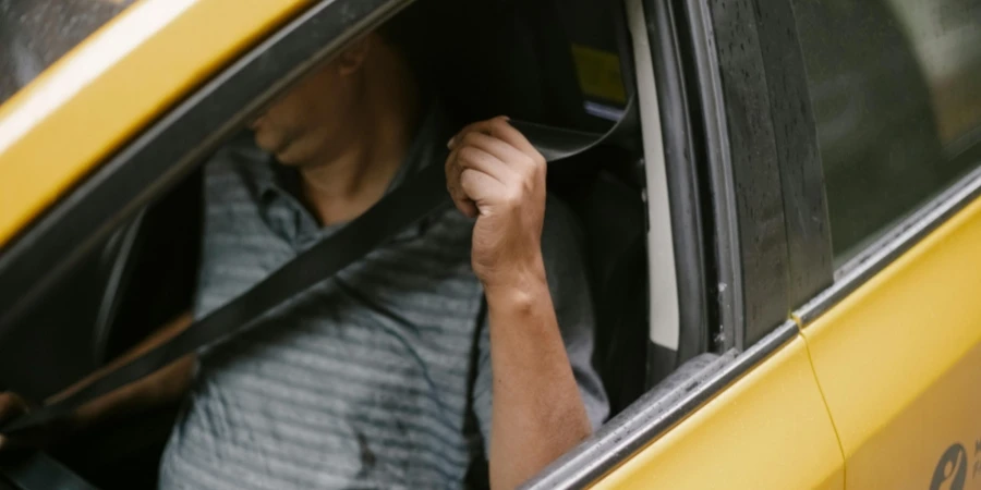 Unrecognizable male driver sitting in cab and fastening seat belt