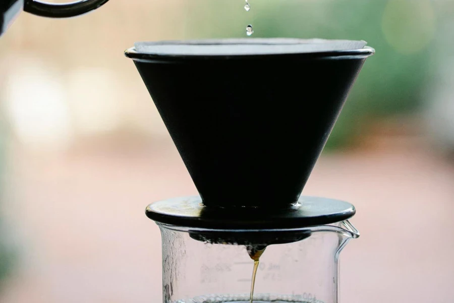 Unrecognizable person brewing aromatic pour over coffee in garden