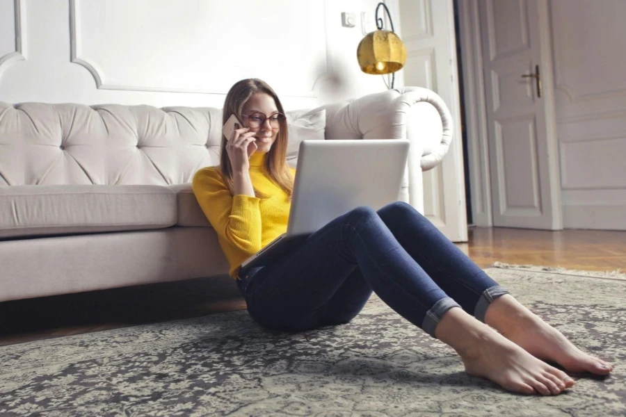 Woman Talks to the Phone Sitting on the Carpet