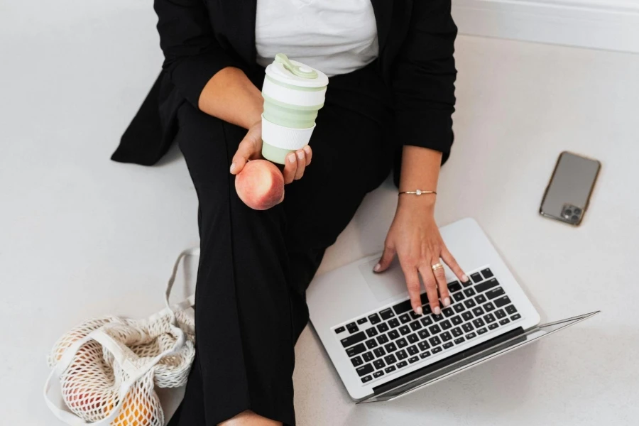 Woman Typing with A Tumbler in Hand