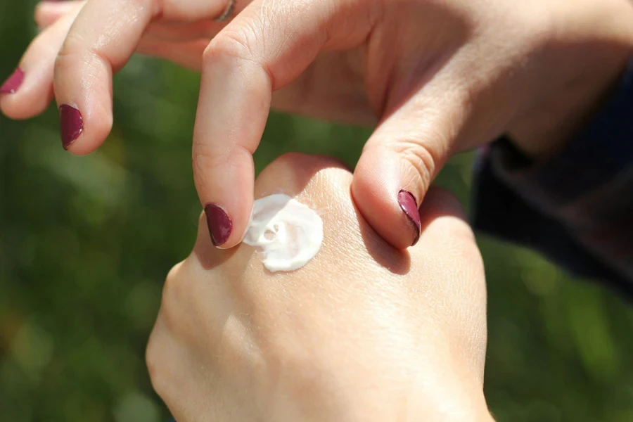 Woman hands with red nail polish using moisturizer