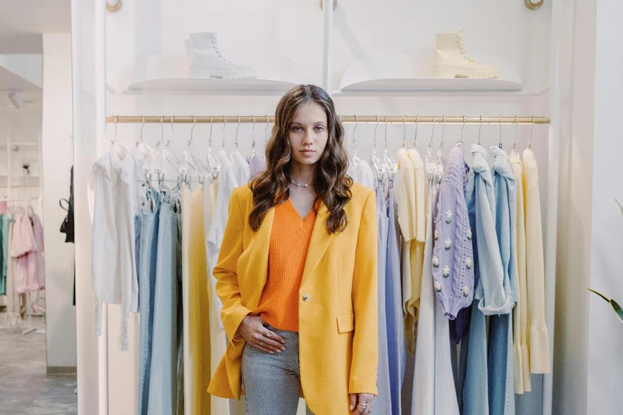 Woman in Yellow Blazer Standing Near Clothes Rack