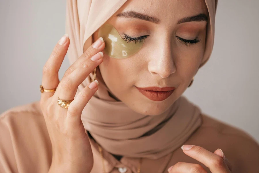 Woman in hijab using a green under-eye patch