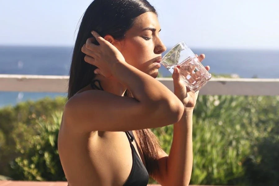 Woman wearing a black bikini drinking water