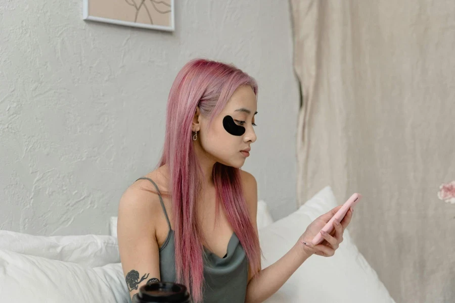 Woman with pink hair using charcoal under-eye patches