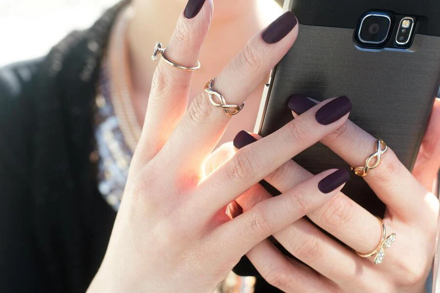 Woman’s hands holding a phone matte nails