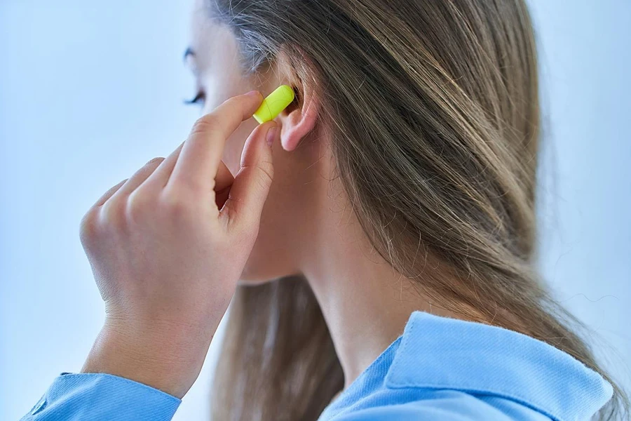 Young brunette woman using earplugs for noise protection