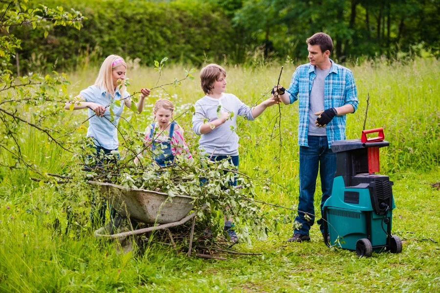 Young family grinding branches while working in their orchard