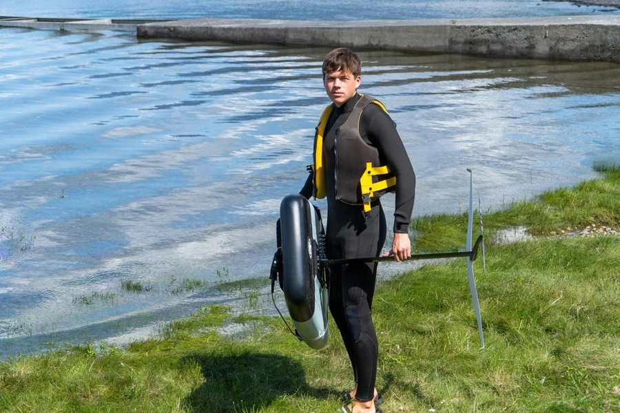 Young man with a foil and board ready to hit the water