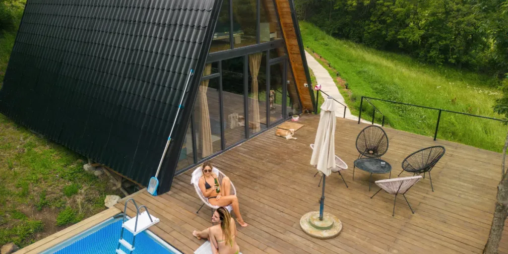 A-frame house alongside wooden deck with a swimming pool