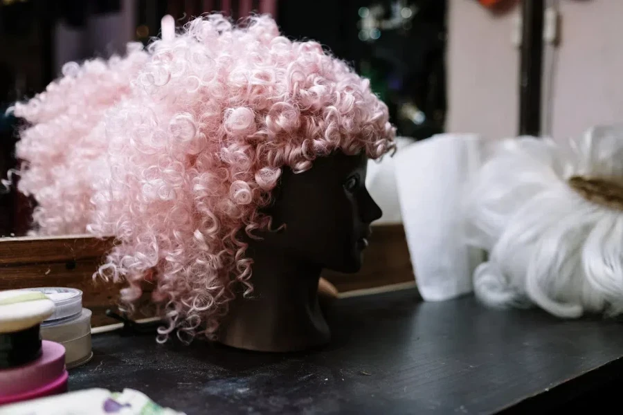 A pink, curly wig on a mannequin head