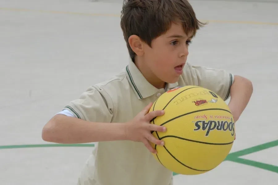 An 8-year-old boy playing with a mini basketball on the court