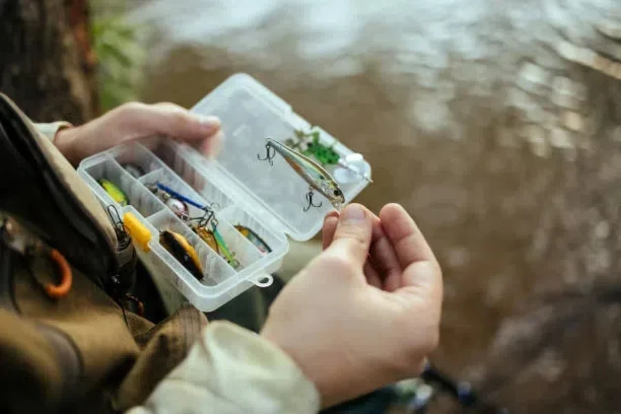 Angler holding fishing lures next to freshwater lake