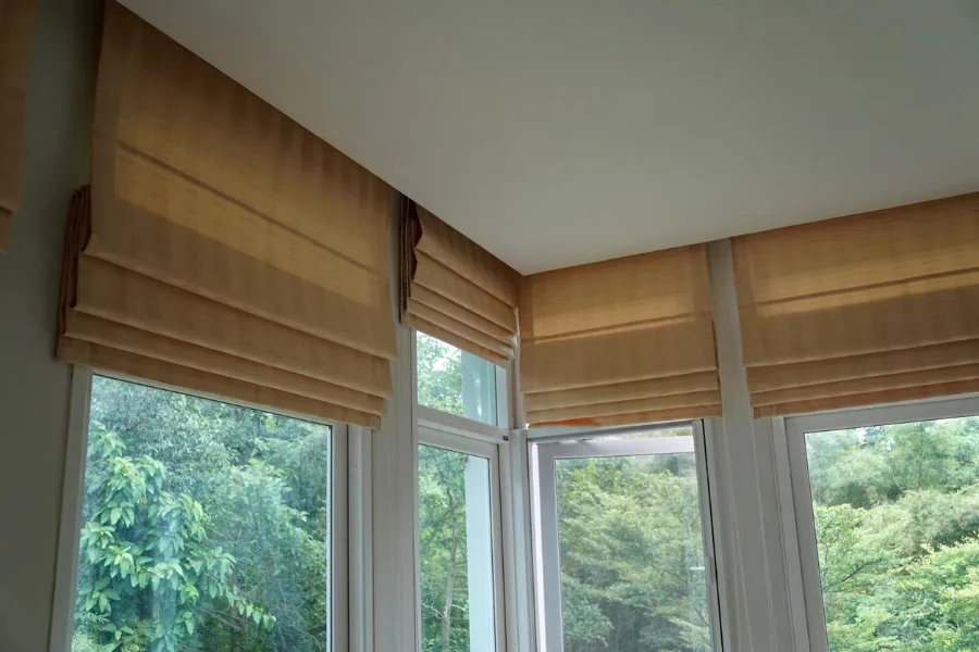 brown Roman blind shades in a living room surrounded by trees