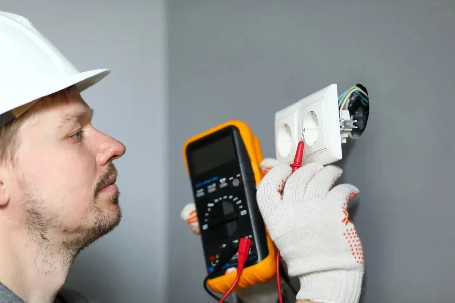 Electrician in helmet measures voltage level