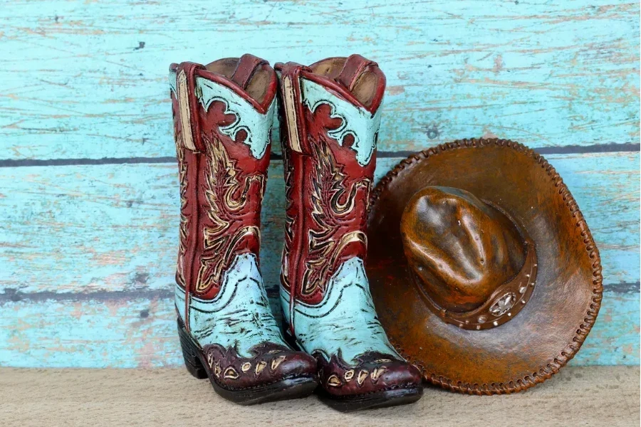 Embroidered cowboy boots and brown hat on wooden background