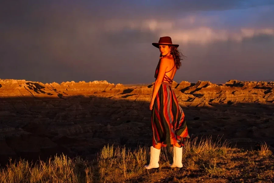 Female model wearing boots, a hat, and a colorful dress