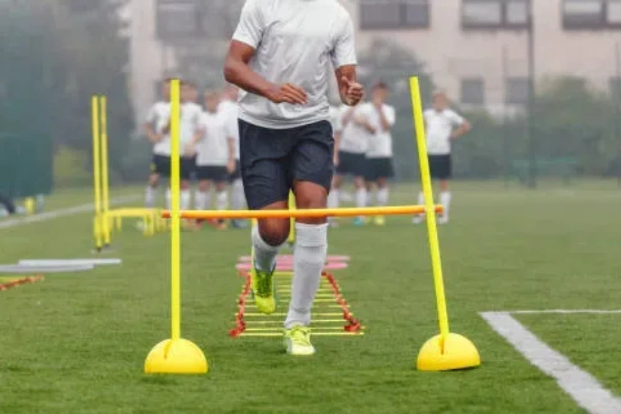 Football player using agility ladder and adjustable hurdles