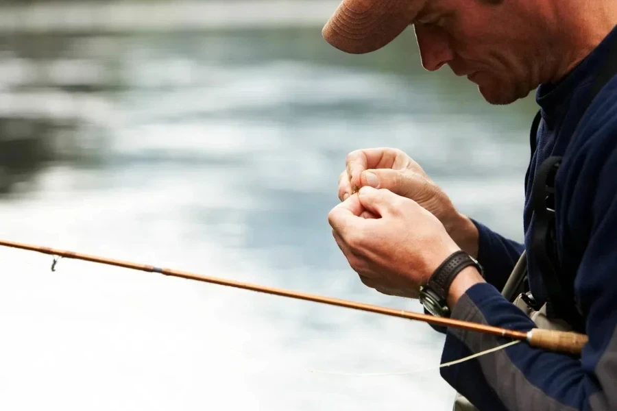 Man preparing to set fishing lure on hook of rod