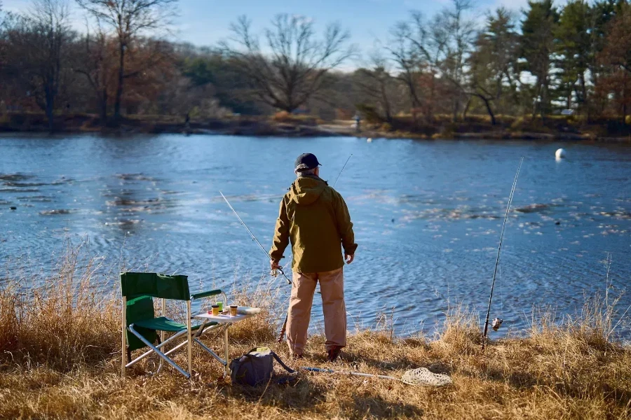 Man standing next to water with different fishing rods