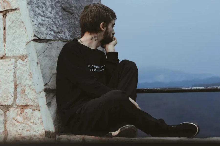 Man wearing all-black crewneck, jeans, and shoes