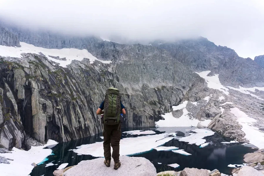 Man wearing green adventure backpack in the mountains