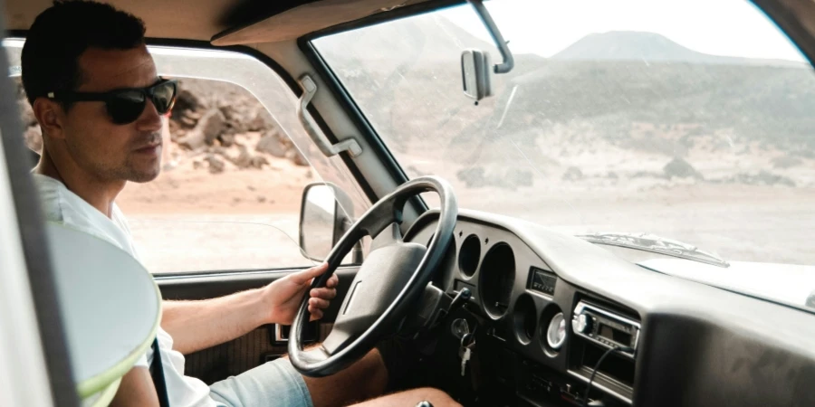 man wearing white crew-neck shirt holding steering wheel