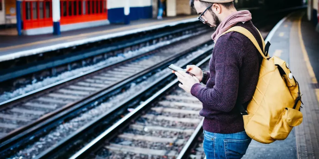 Man wearing yellow cool carry-on backpack next at station