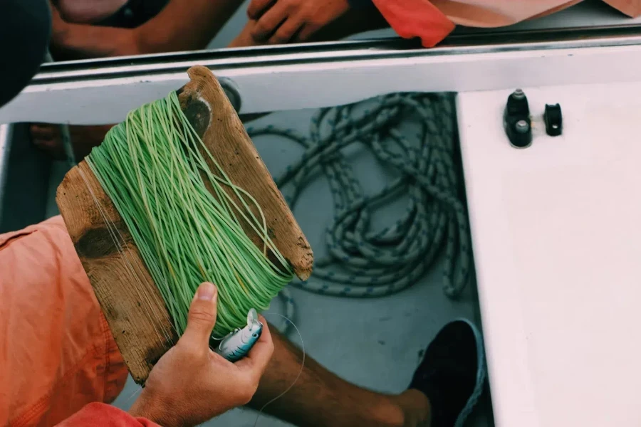 Man with green fishing line holding fishing lure