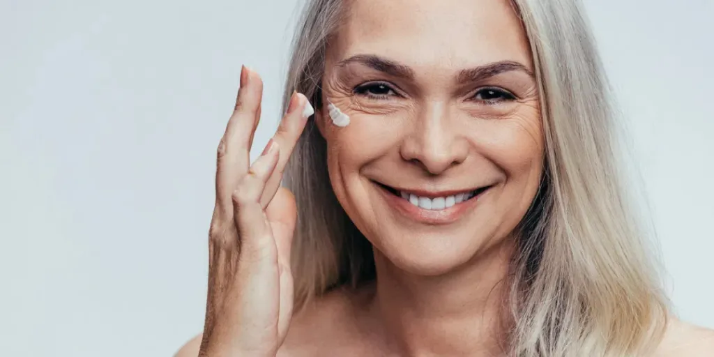 Mature smiling woman using moisturizer