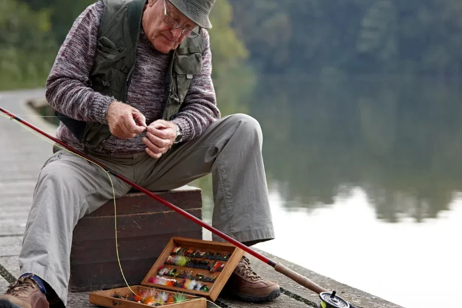 Older man sitting with tackle box and fishing rod