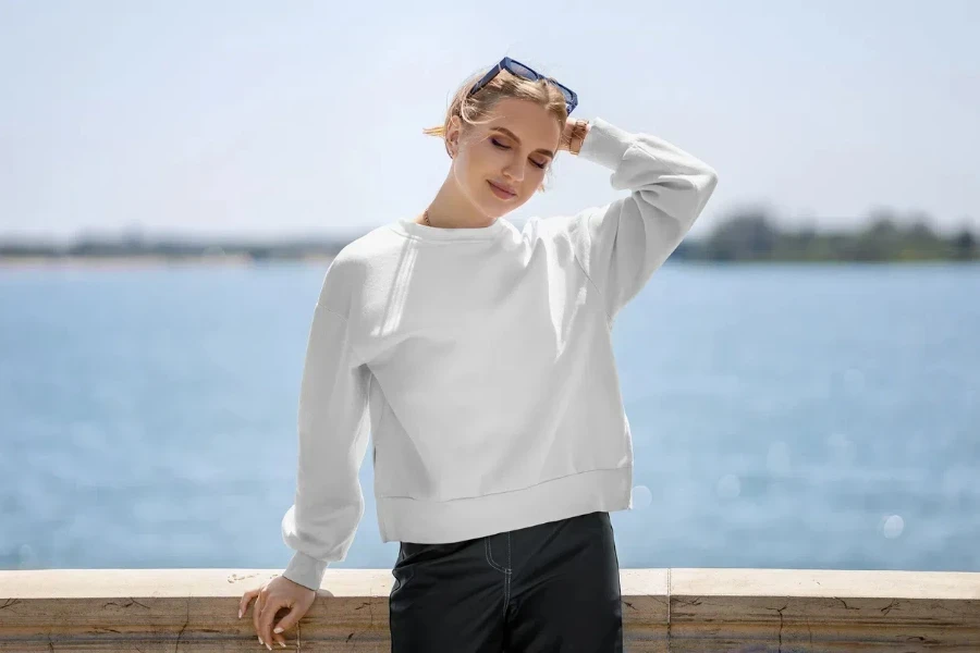 Stylish woman in a white crewneck, brown bracelet, and sunglasses