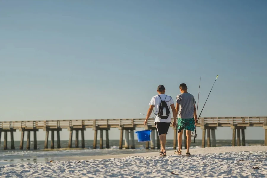 Two men walking across beach with fishing gear