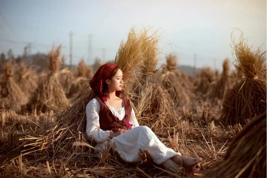 Woman in a bohemian-inspired vest sitting amid hay