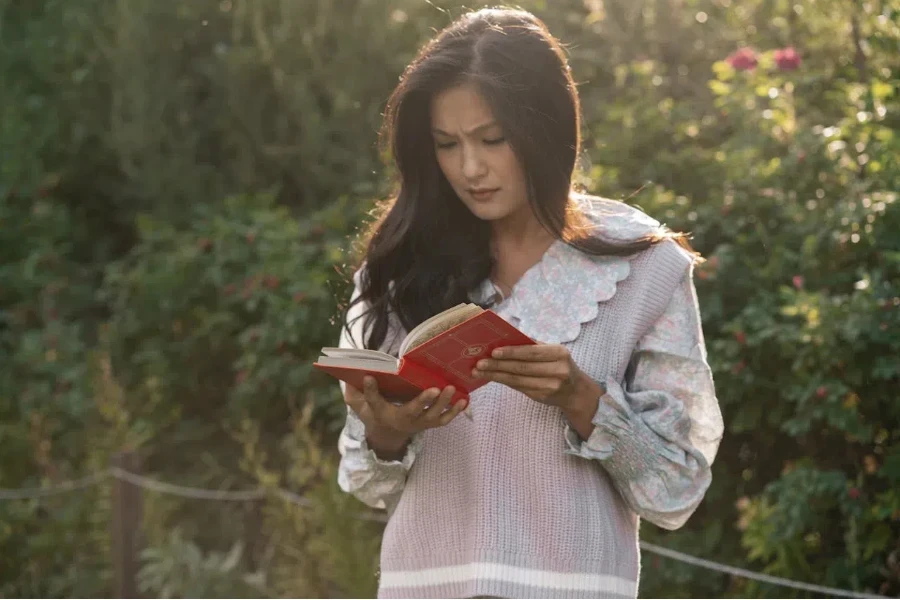 Woman reading in a garden wearing a ruffled vest