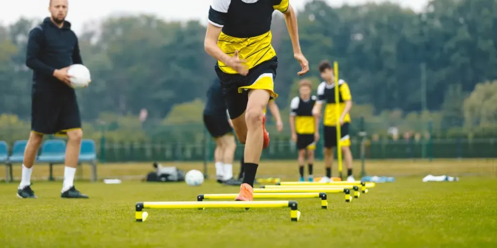 Young boy at football sprinting across low yellow agility hurdles