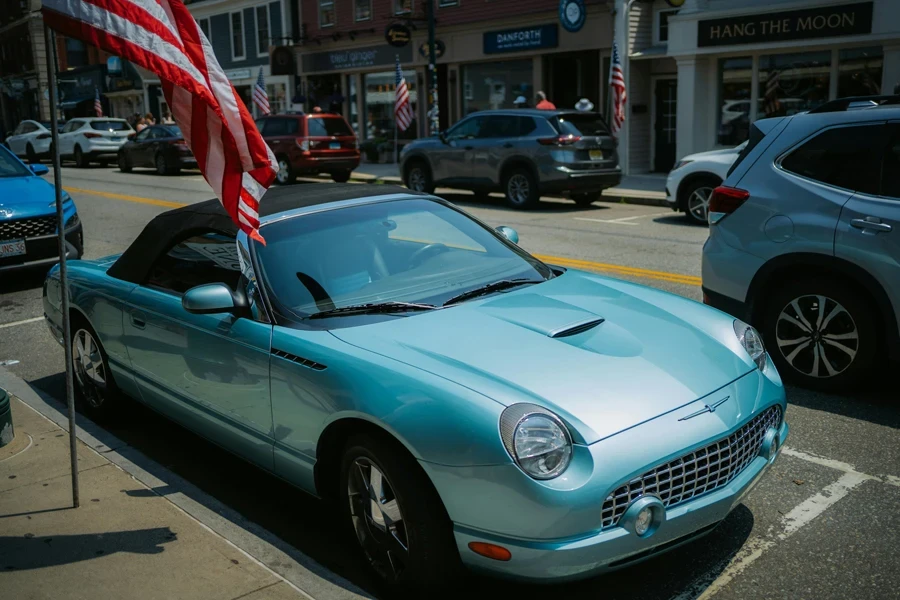 A blue car parked on the street with an american flag