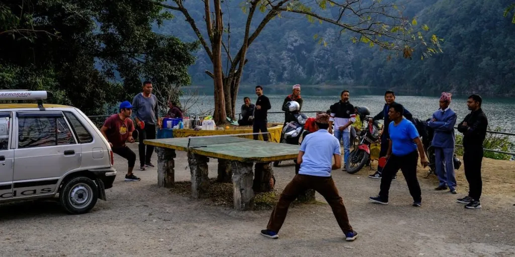 A group of people playing table tennis outdoors