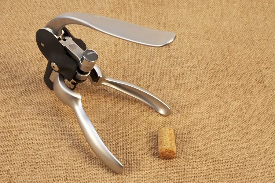 A lever corkscrew next to a wine bottle cork