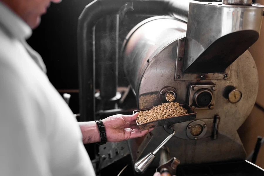 A man checking the nuts in a roasting machine